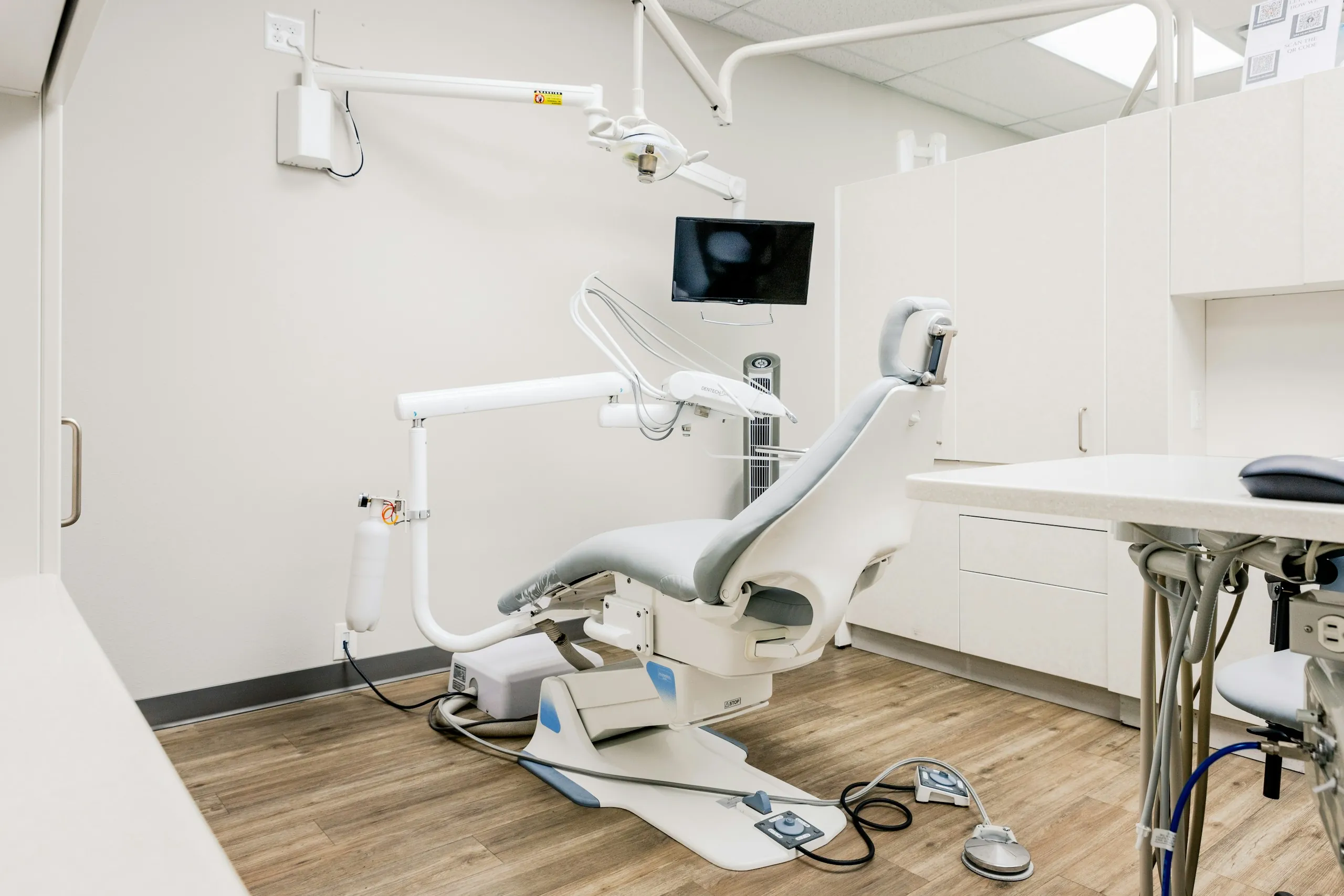 A treatment room with a dental chair, desk and window