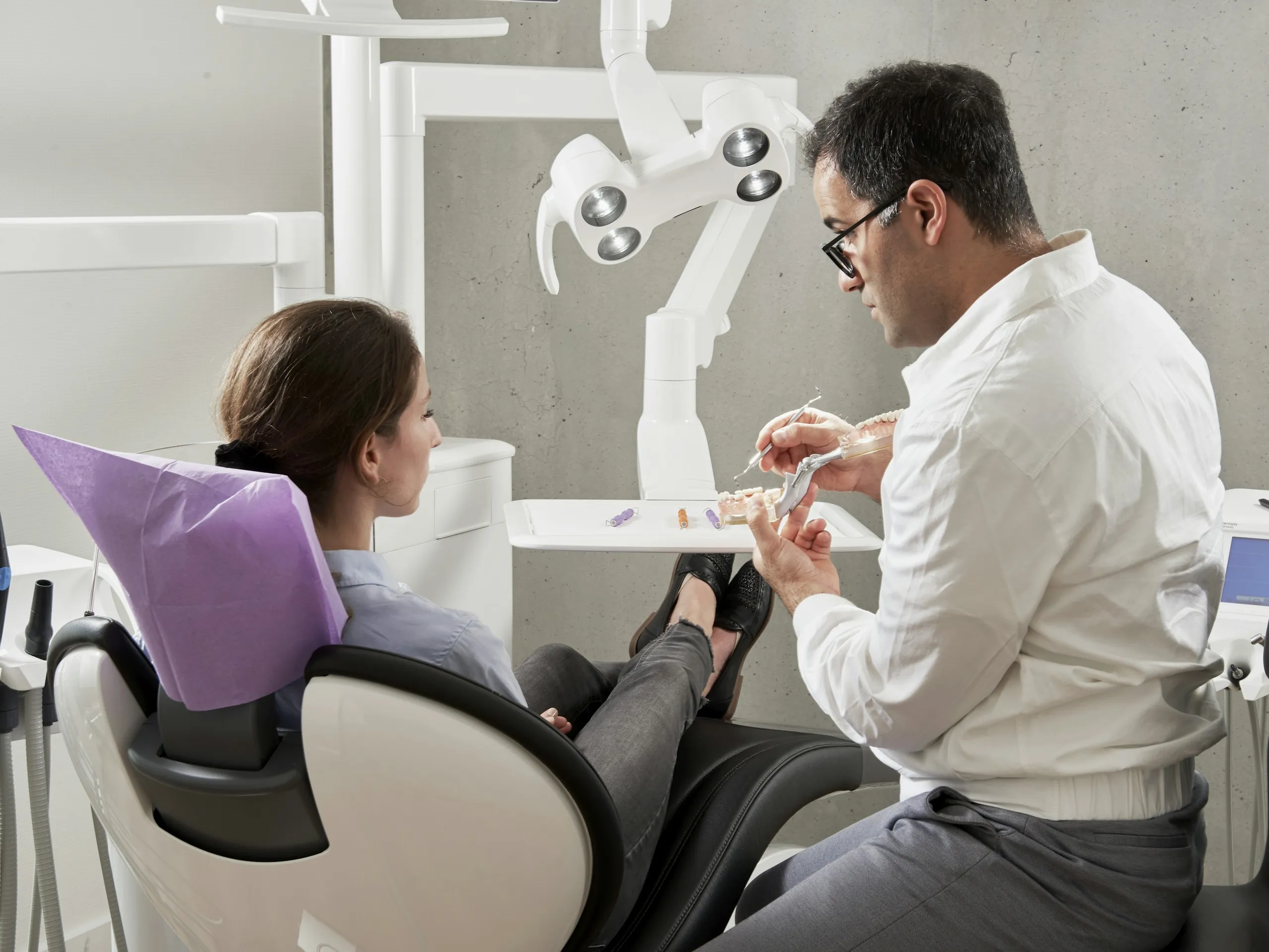 An orthodontist talking with a patient in the treatment chair