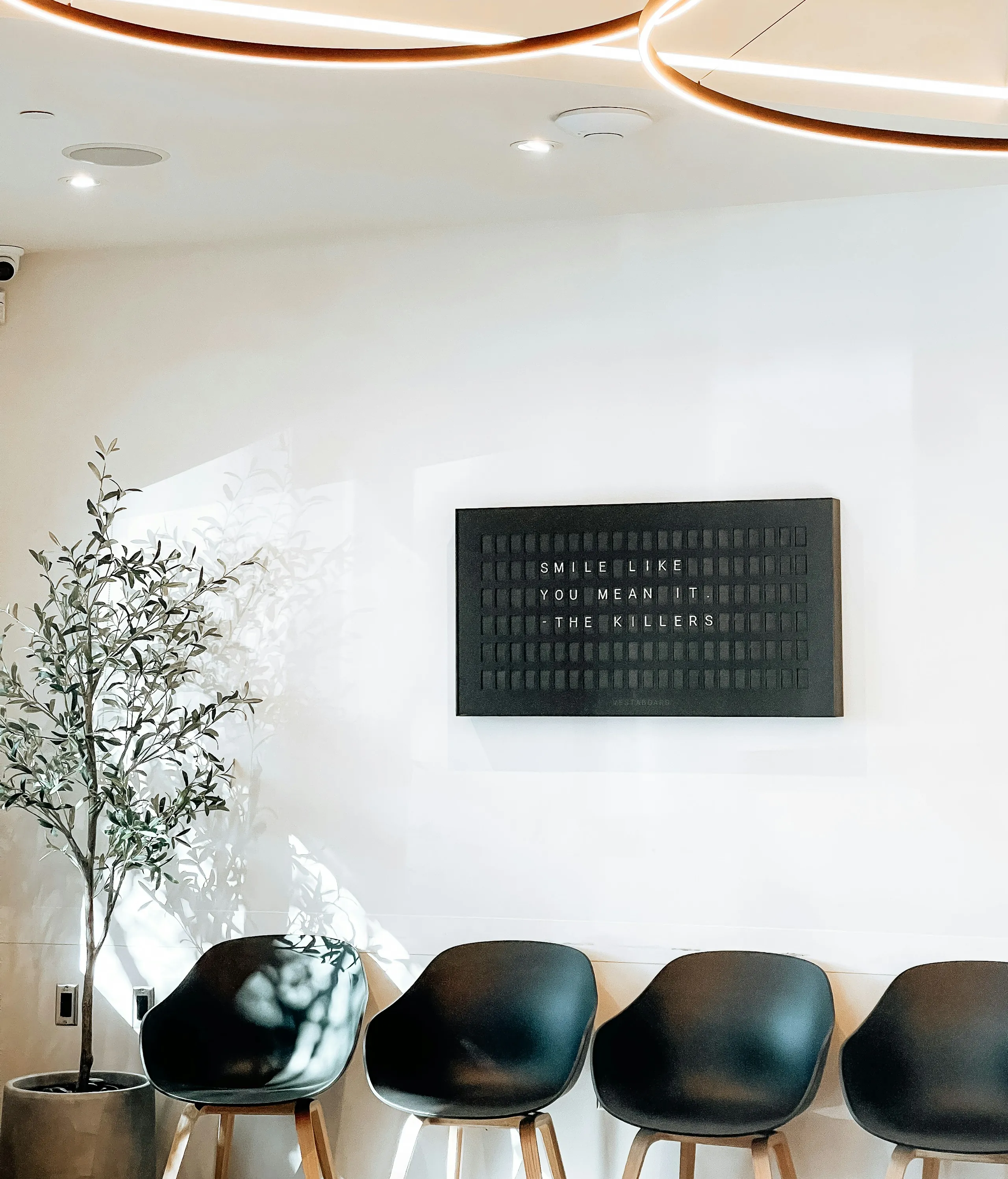 A bright waiting room with black chairs and a framed sign